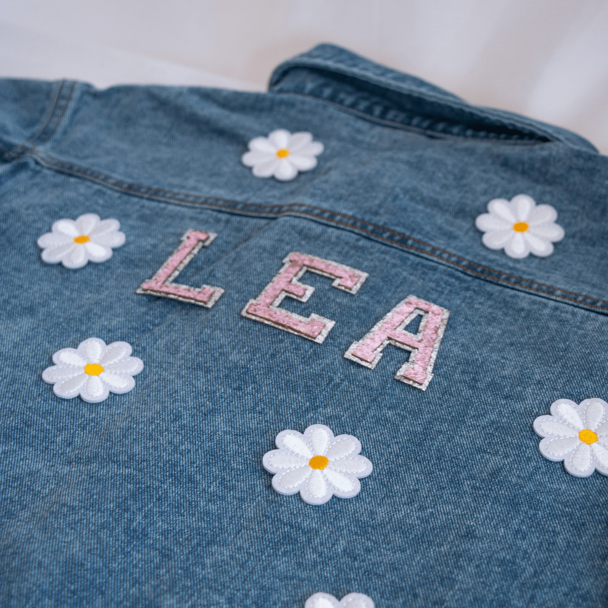 Dunkelblaue Jeansjacke für Kinder mit glitzernden Buchstaben und Blumen – ein kreatives und funkelndes Statement-Piece.