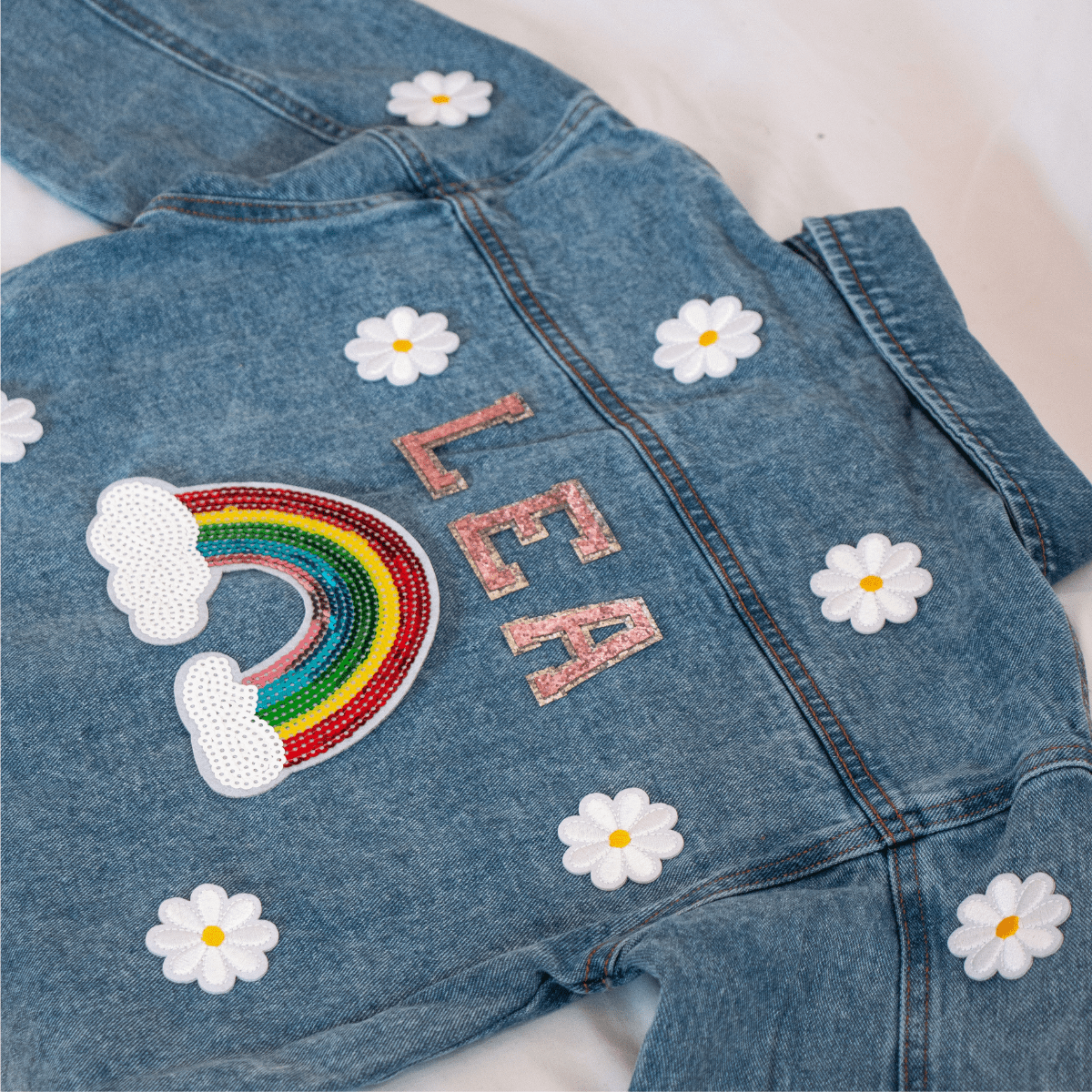 Dunkelblaue Jeansjacke für Kinder mit glitzernden Pailletten-Bügelbildern – ein funkelndes und individuelles Statement-Piece für kleine Modefans.