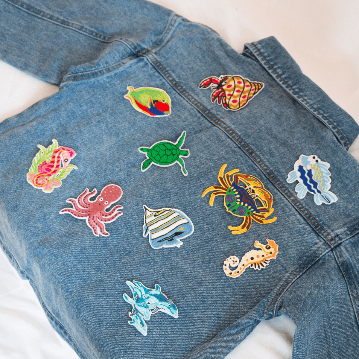 Dunkelblaue Jeansjacke für Kinder mit bunten Meerestieren-Bügelbildern – ein kreatives und maritimes Statement-Piece für kleine Abenteurer.